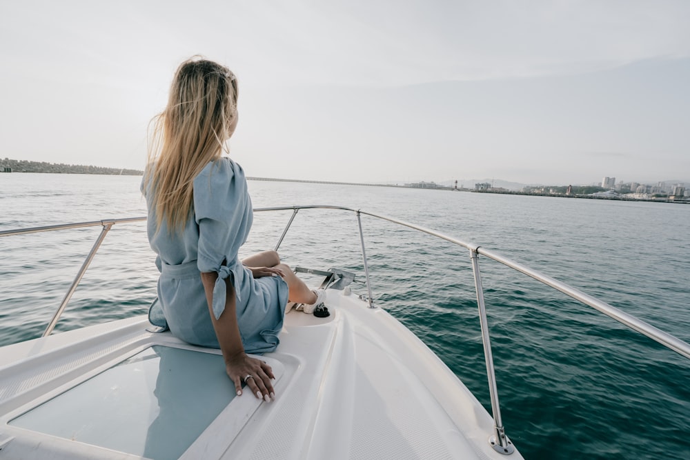 Mujer en camisa blanca de manga larga sentada en barco blanco durante el día