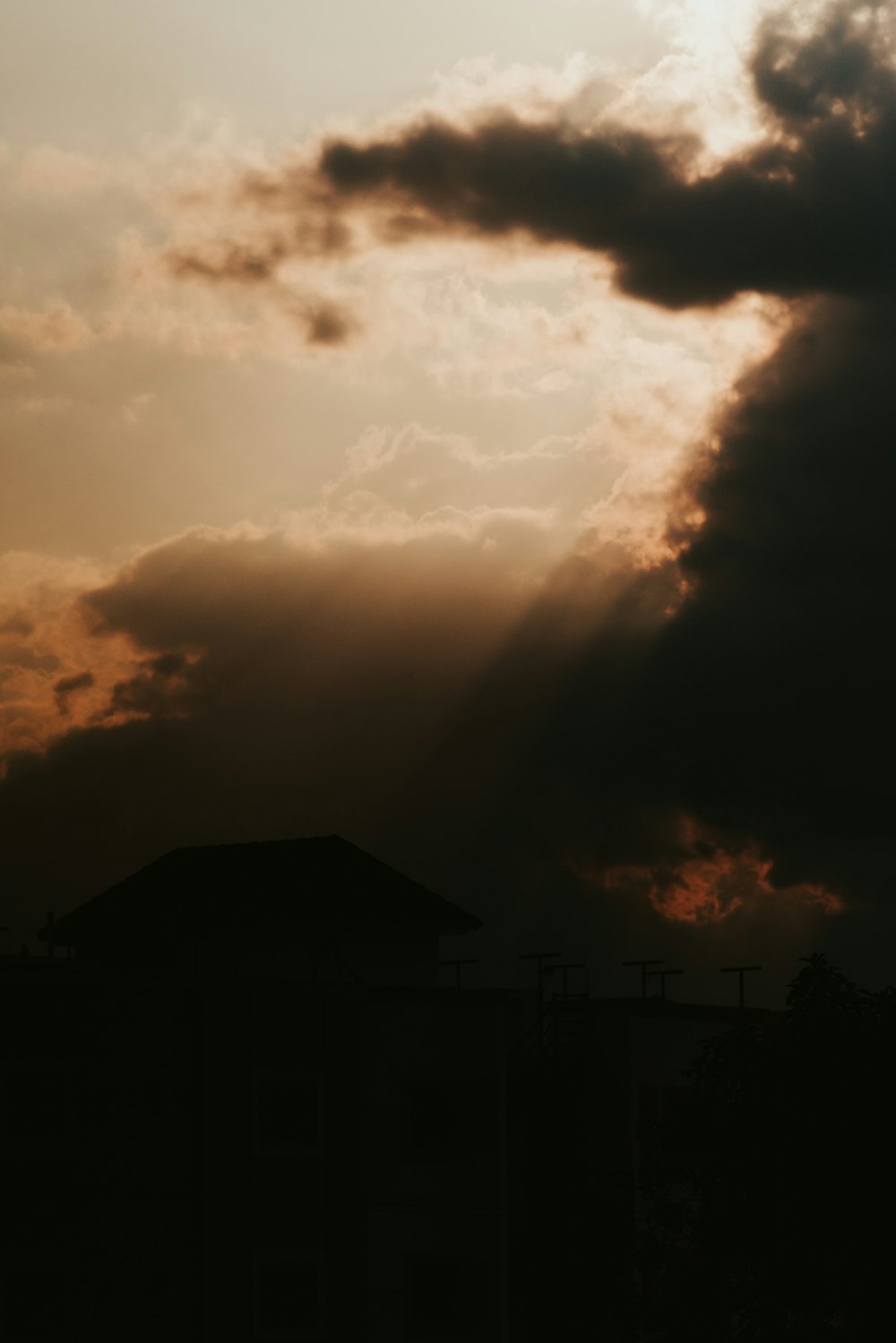 silhouette of house under cloudy sky during sunset