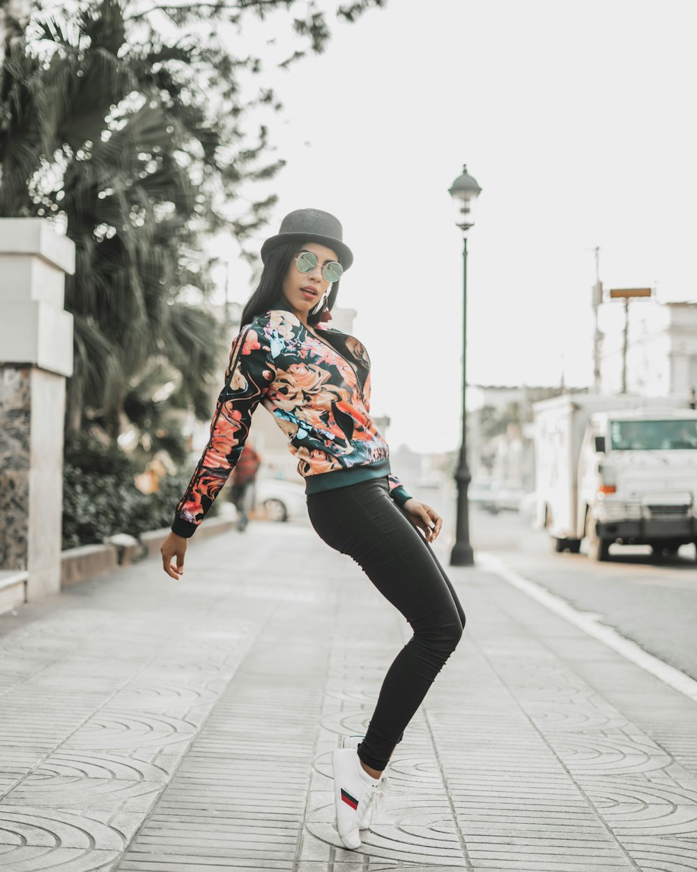 woman in red and blue jacket and black pants walking on sidewalk during daytime