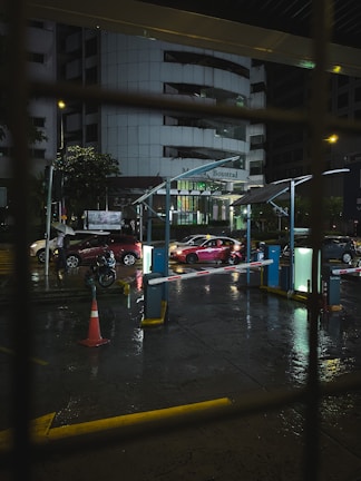 Automated parking barrier gate in action at a commercial complex, illuminated at dusk.