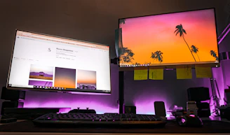 A minimalist workspace with dual monitors displaying cinematic website layouts.