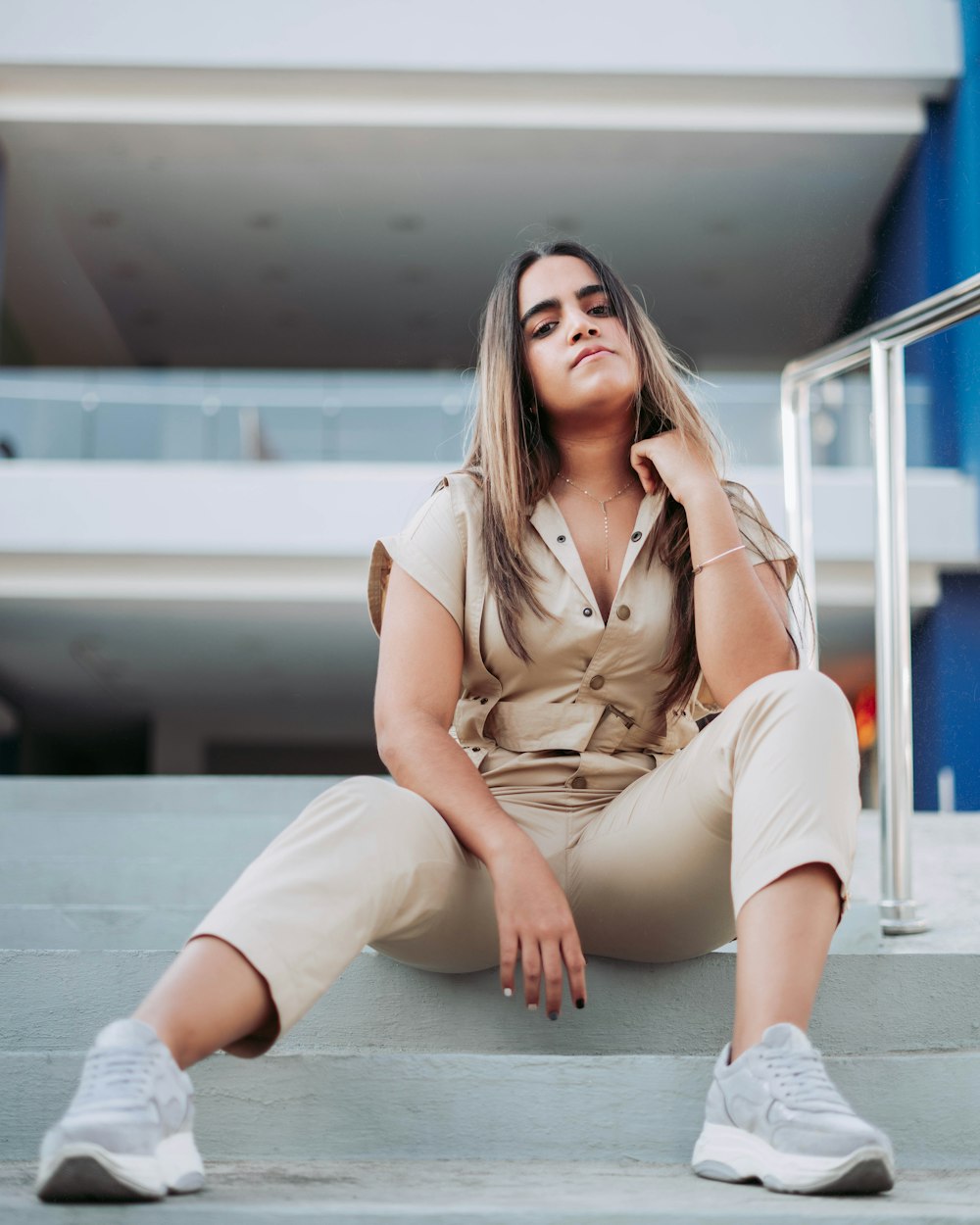 woman in brown button up shirt and white pants sitting on white concrete floor