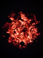 Burning test image showing a glowing cube briquette with minimal smoke against a dark backdrop.