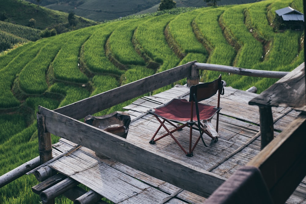 Chaise pliante rouge et noire sur terrasse en bois marron