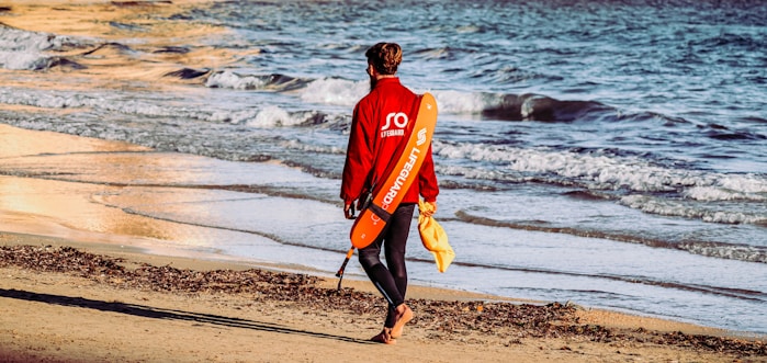 A lifeguard with walkie talkie, wearing a wetsuit and jacket, ready to respond to a water emergency
