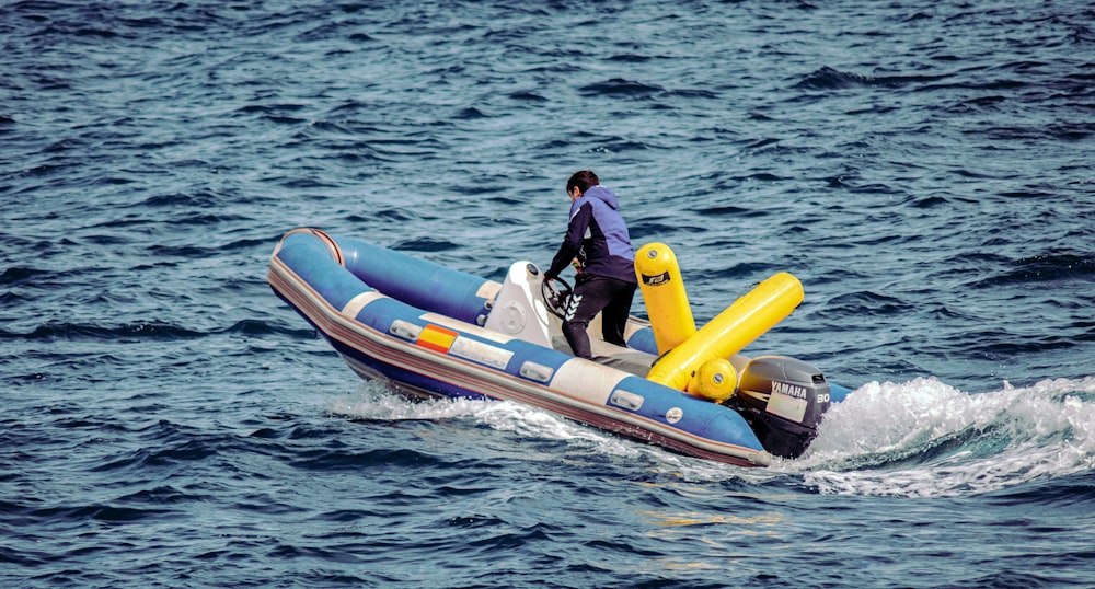 Mann in schwarzer Jacke fährt tagsüber auf einem orange-weißen Schlauchboot