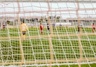 Soft focus on a scoreboard showing 'Coming Soon' with the soccer field in the background.
