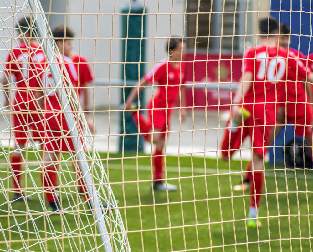 Fußballspieler im roten Trikottrikot spielen tagsüber Fußball