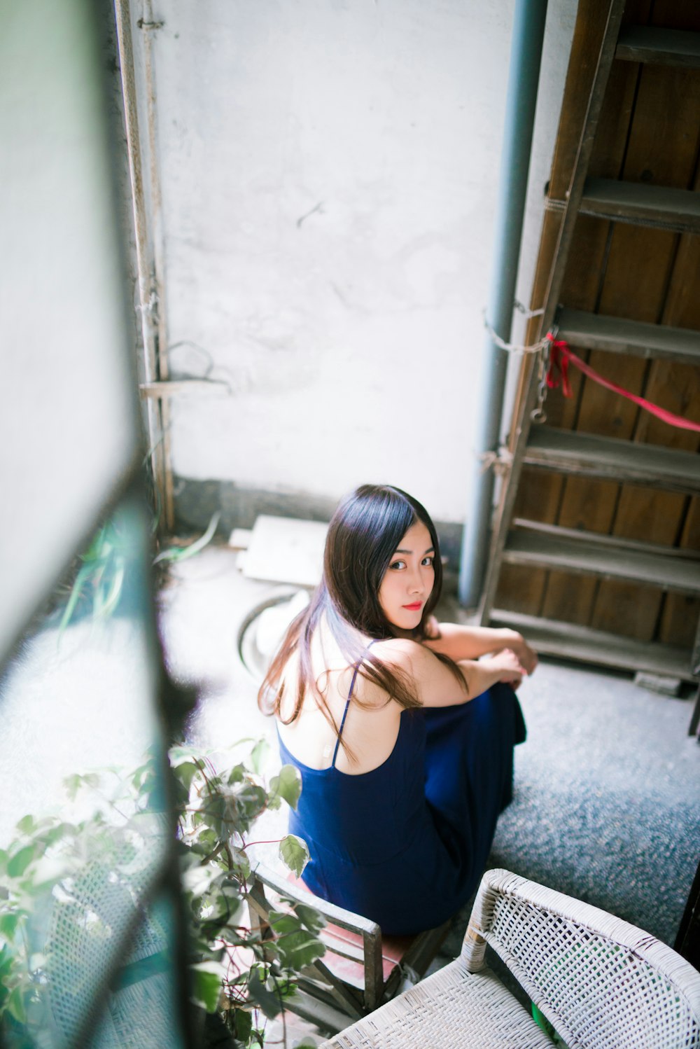 woman in blue spaghetti strap dress sitting on stairs