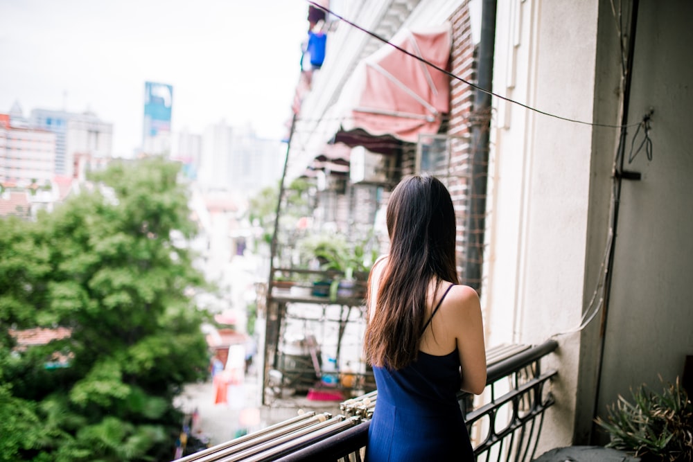 woman in blue sleeveless dress standing on the sidewalk during daytime