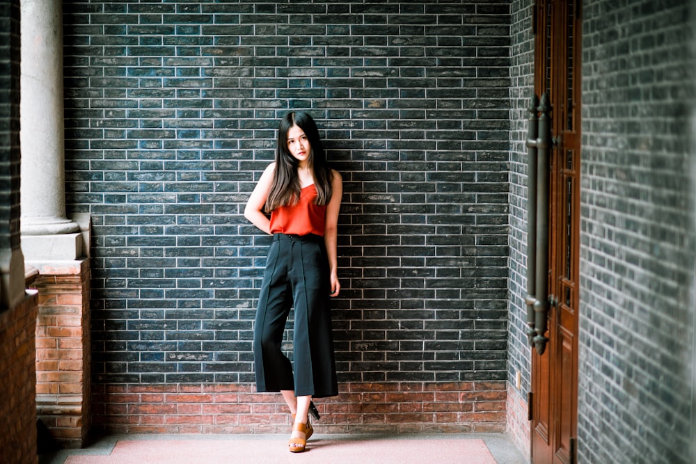 woman in gray sleeveless dress standing beside brick wall