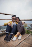 one man and woman sitting on wooden bridge