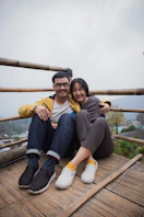 one man and woman sitting on wooden bridge