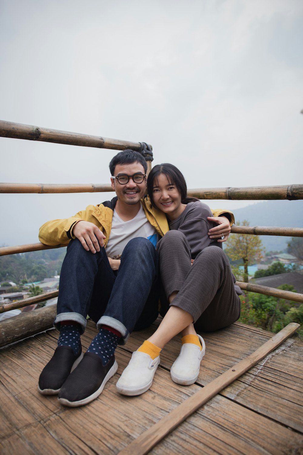 2 women sitting on wooden bridge