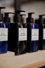 Close-up of premium beard care products displayed on a charcoal gray shelf with golden details.
