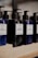 Several bottles of beard shampoo and conditioner with black pump dispensers are displayed on a wooden shelf. The central bottle is labeled 'Murdock London Beard Shampoo.' The bottles are dark blue and black, creating a sleek and modern look.