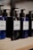 Several bottles of beard shampoo and conditioner with black pump dispensers are displayed on a wooden shelf. The central bottle is labeled 'Murdock London Beard Shampoo.' The bottles are dark blue and black, creating a sleek and modern look.