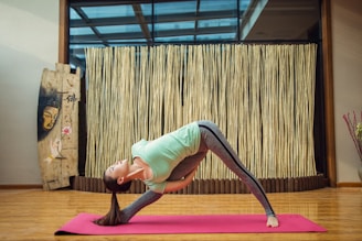 woman in green tank top and gray leggings doing yoga