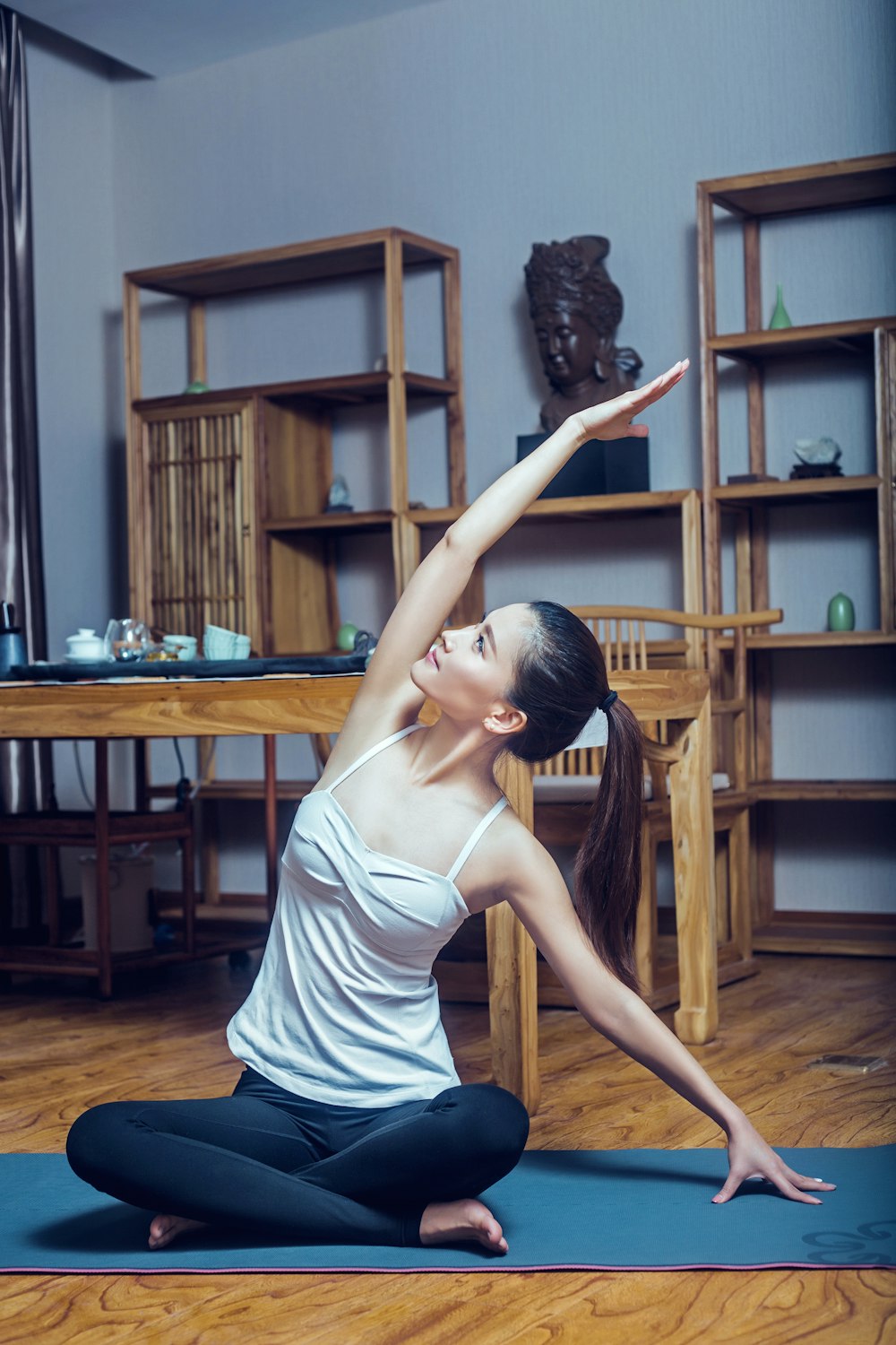 woman in white tank top and black and white striped skirt sitting on brown wooden chair