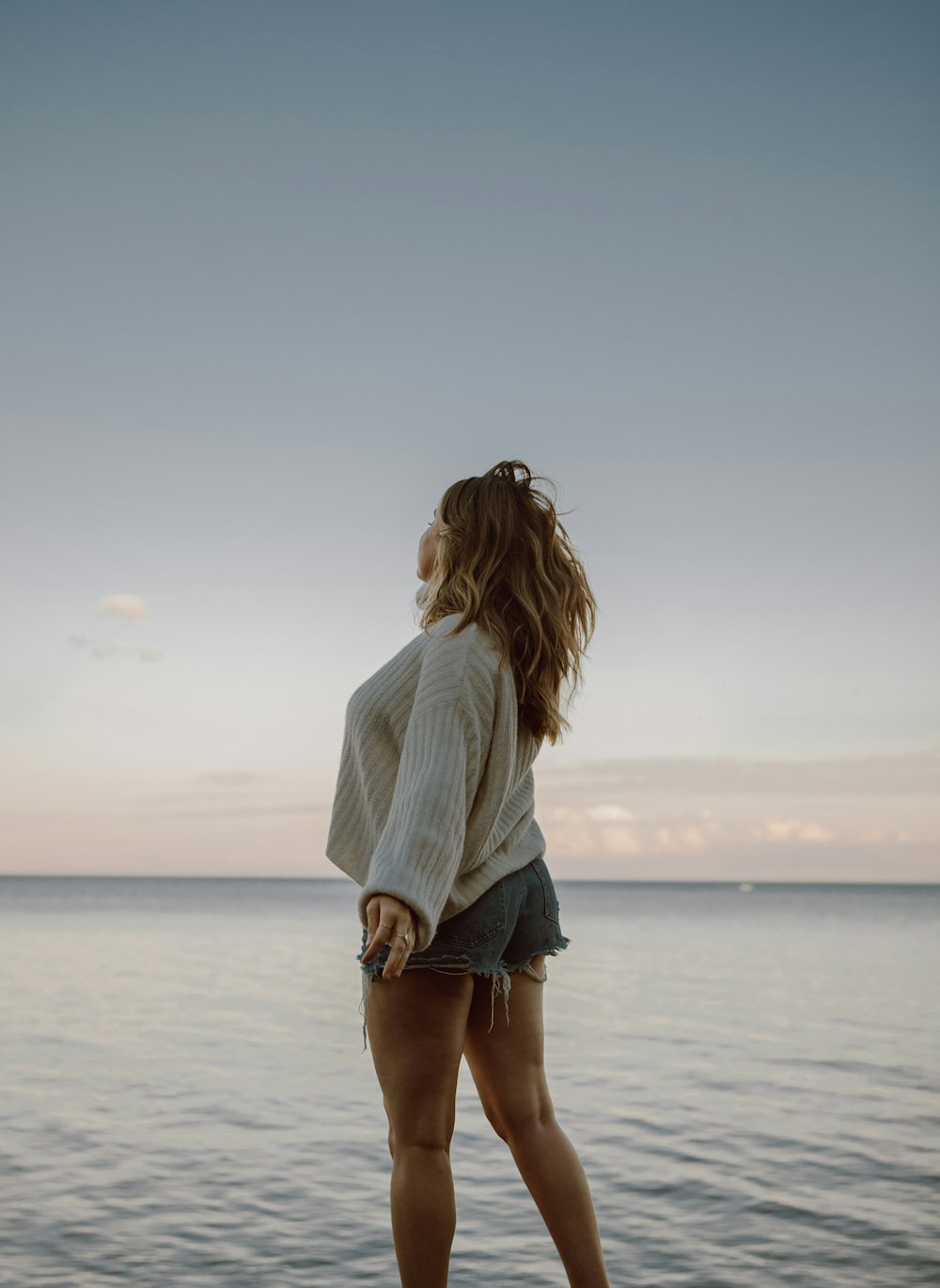 woman in white and blue striped long sleeve shirt standing on beach during daytime