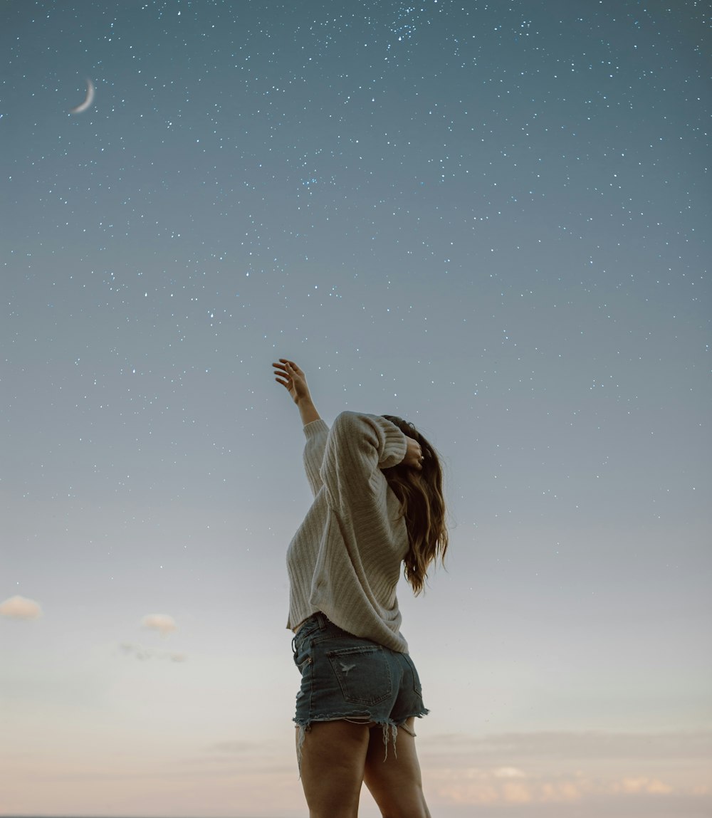 woman in gray hoodie and black pants raising her hands