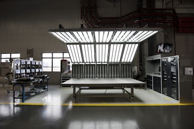 Modern workspace with dismantled refrigerator components neatly arranged on a metallic table under blue and green lighting.