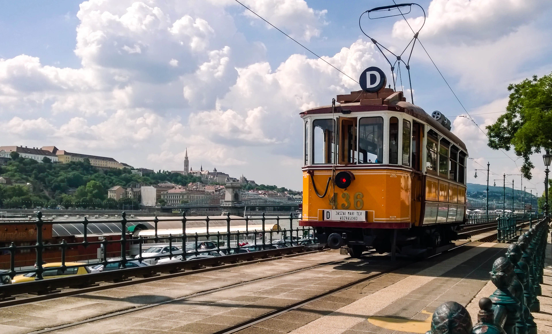 yellow and white tram on bridge under white clouds and blue sky during daytime