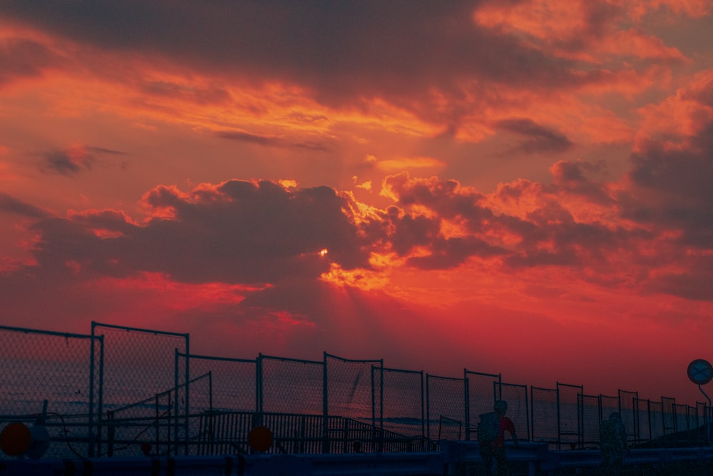 silhouette of people standing on bridge during sunset