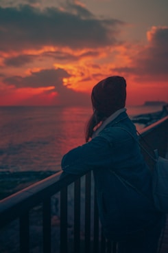 man in black jacket standing near railings during sunset