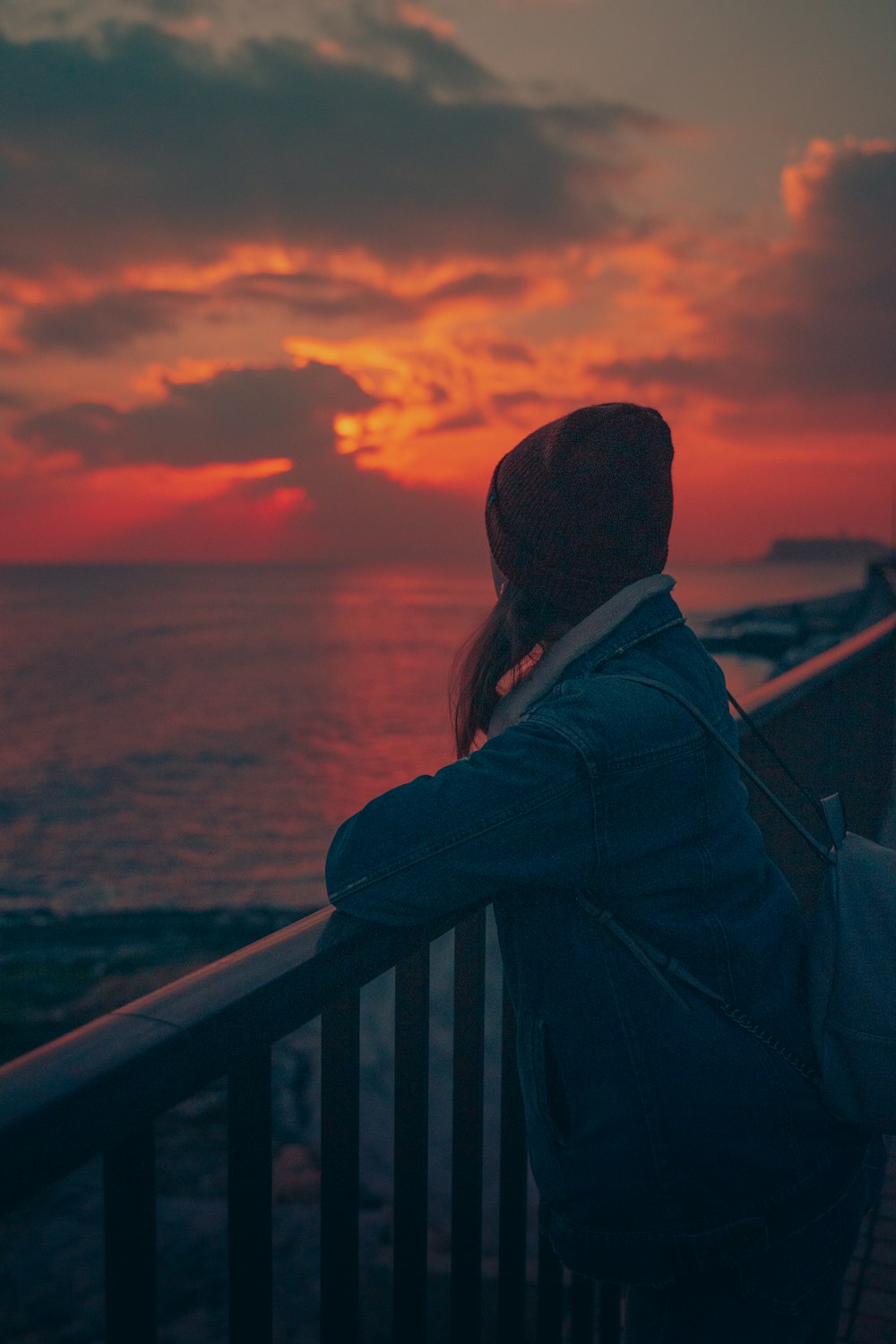 man in black jacket standing near railings during sunset