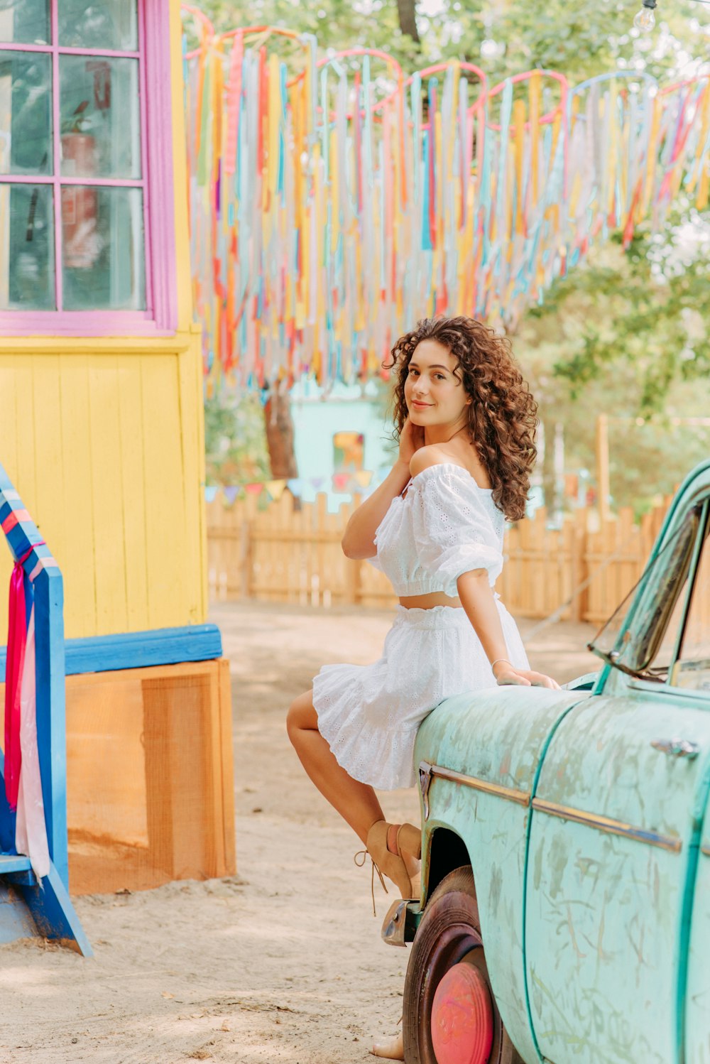 woman in white dress sitting on blue car during daytime