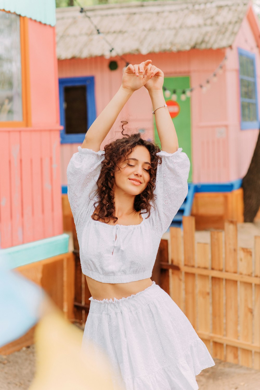 a woman in a white dress is holding her arms above her head