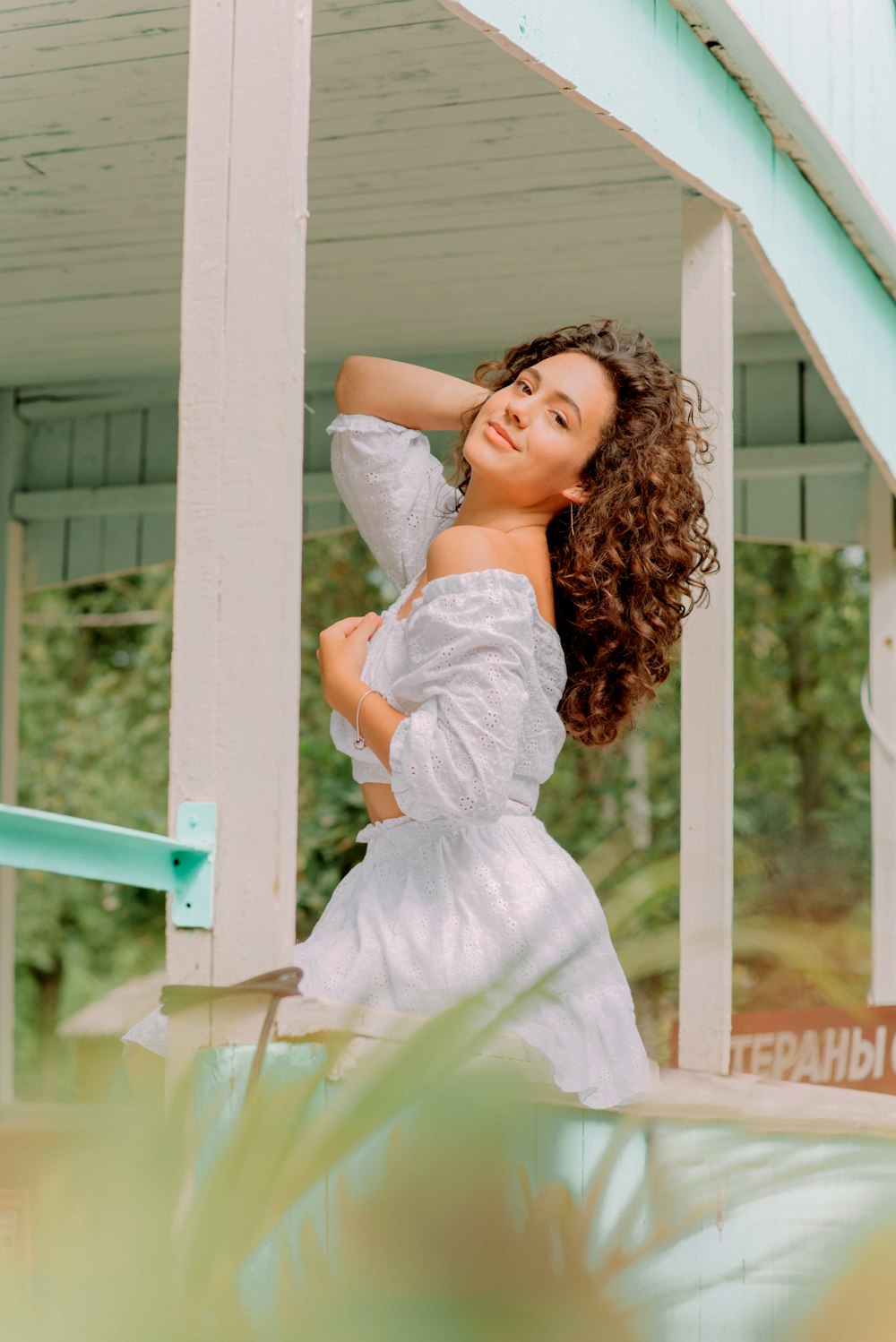 girl in white dress sitting on white wooden fence during daytime