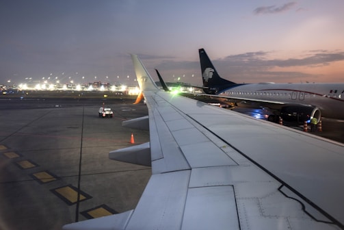 A dramatic twilight shot of a plane landing with city lights of Munich glowing in the background.