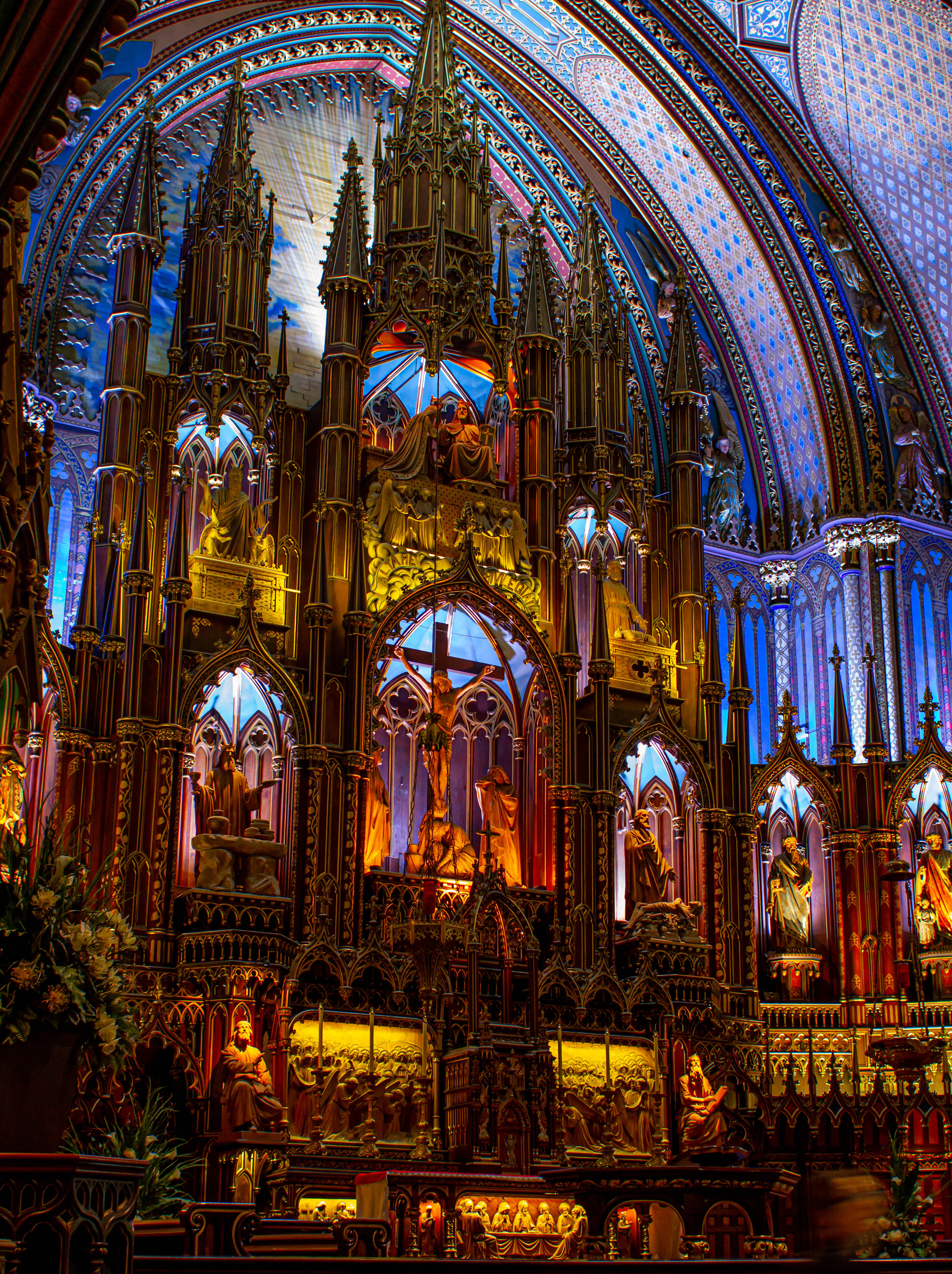 The carved and gilded altarpiece of Notre-Dame Basilica in Old Montreal, lit in gold beneath the church's deep blue star-spangled vaulted ceiling