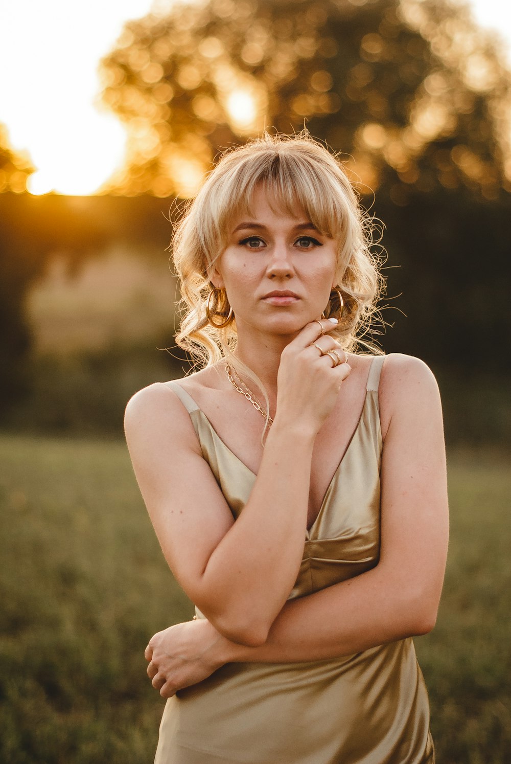 girl in white tank top standing on grass field during sunset