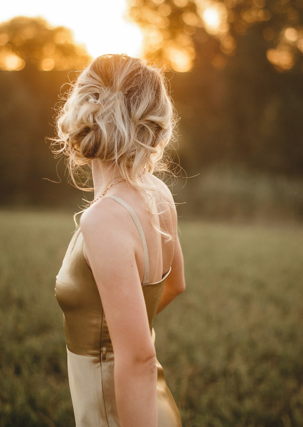 woman in white tank top standing on green grass field during daytime