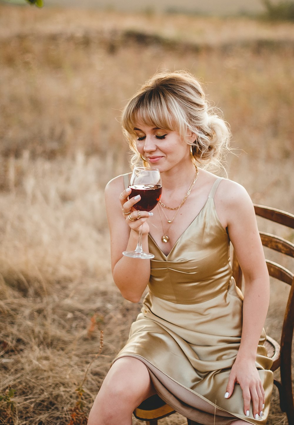 woman in beige sleeveless dress holding clear drinking glass