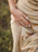 Close-up of a woman's hand adorned with éclat d'or rings, resting on a champagne gold fabric.