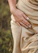 Close-up of a woman's hand wearing delicate gold rings with a soft natural background.