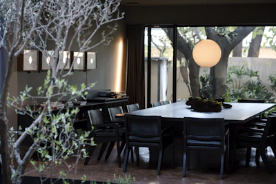 A modern dining area showcasing a dark wood table with sculptural chairs and ambient pendant lighting.