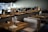 Tables set with wine glasses and cloth napkins inside a dimly lit, modern restaurant featuring wooden furniture and soft lighting.