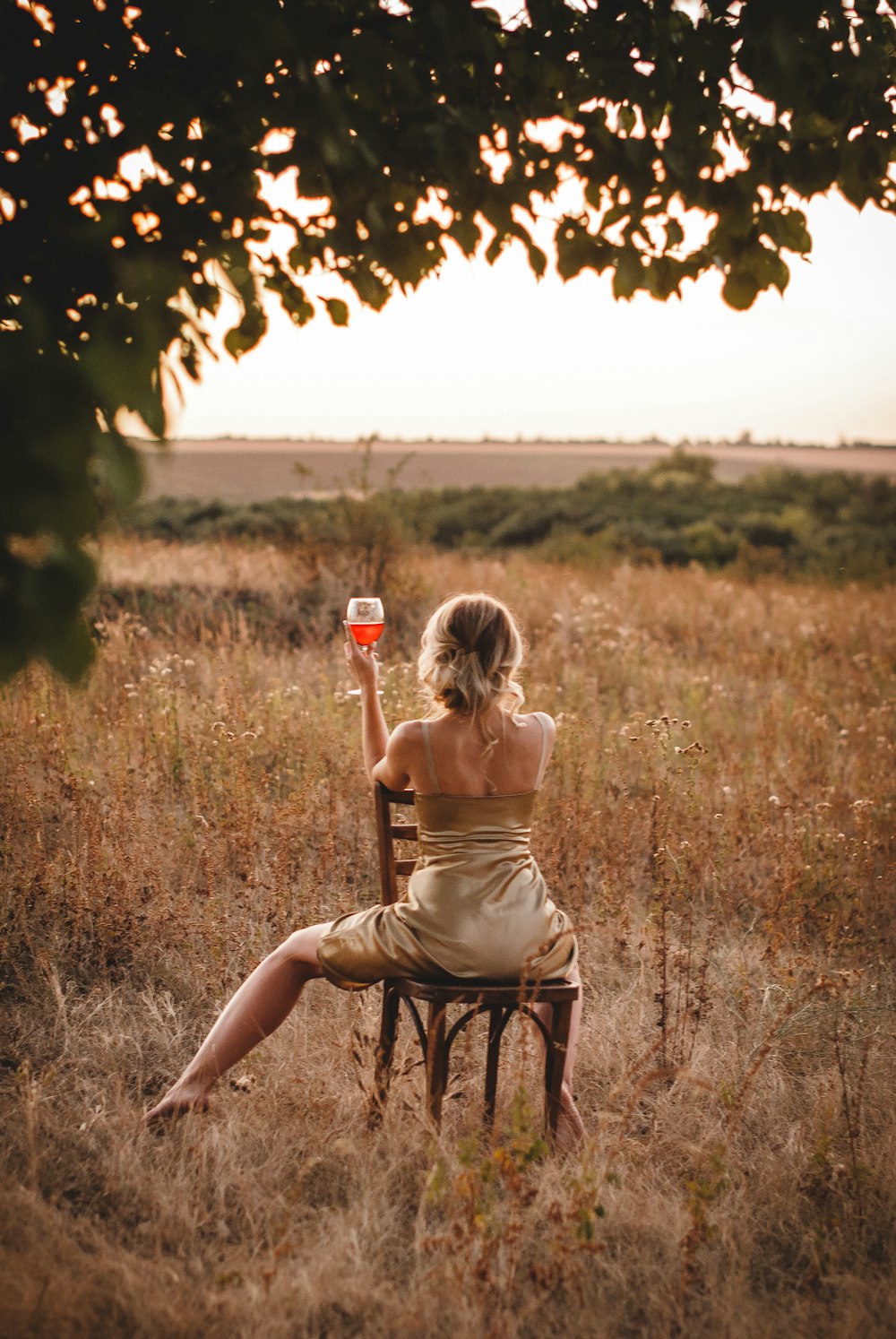 woman in brown tank top and black shorts standing on brown grass field during daytime