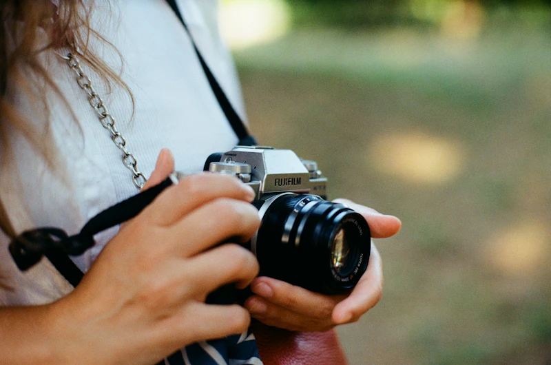 Woman in a white shirt holding a black and silver camera
