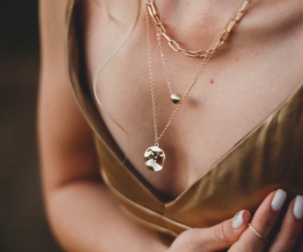 woman in gold sleeveless dress wearing gold necklace