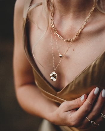 woman in gold sleeveless dress wearing gold necklace