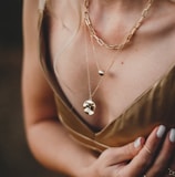 woman in gold sleeveless dress wearing gold necklace