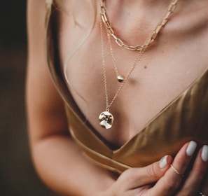 woman in gold sleeveless dress wearing gold necklace