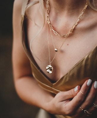 woman in gold sleeveless dress wearing gold necklace