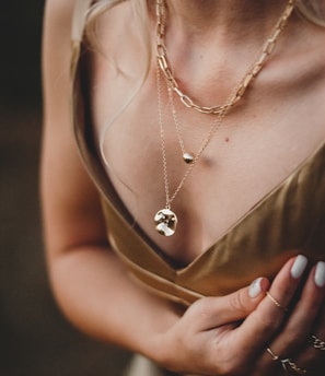 woman in gold sleeveless dress wearing gold necklace